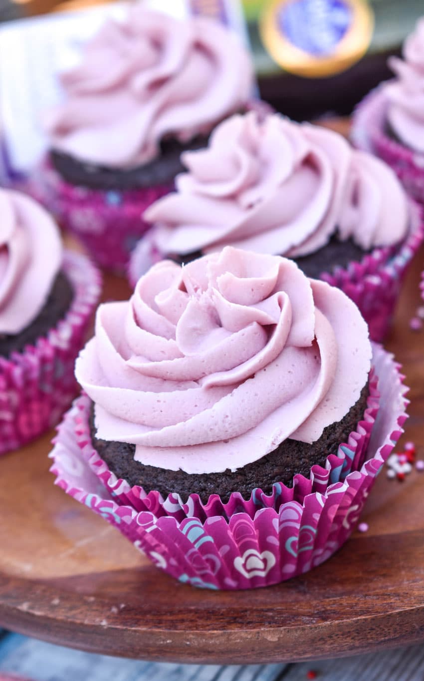 dark chocolate cupcakes with red wine buttercream frosting on a wooden cake stand