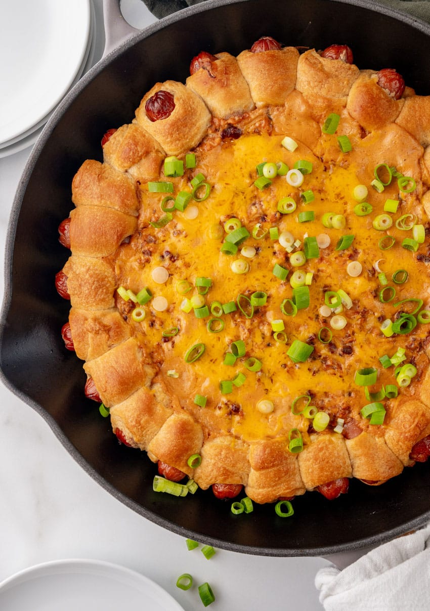 a chili cheese dog dip ring in a black cast iron skillet
