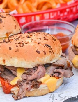 copycat arby's roast beef and cheddar sandwiches on a crinkled piece of white parchment paper