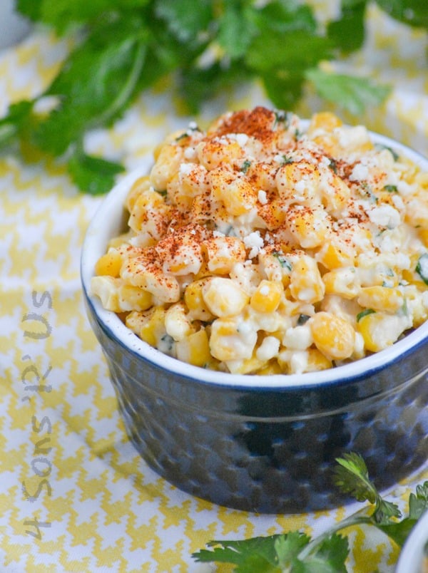 Mexican Street Corn Salad in a blue ramekin on a yellow and white cloth napkin with fresh cilantro in the background