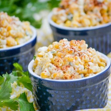 MEXICAN STREET CORN SALAD IN THREE SMAL BLUE RAMEKINS WITH FRESH HERBS ON THE SIDE