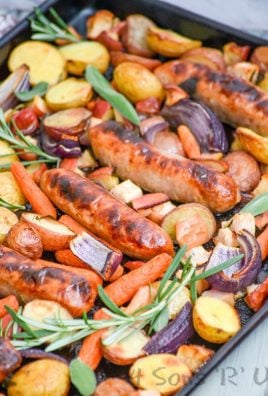 sausage, apple, and herb sheet pan supper shown on a dark sheet pan on a gray background