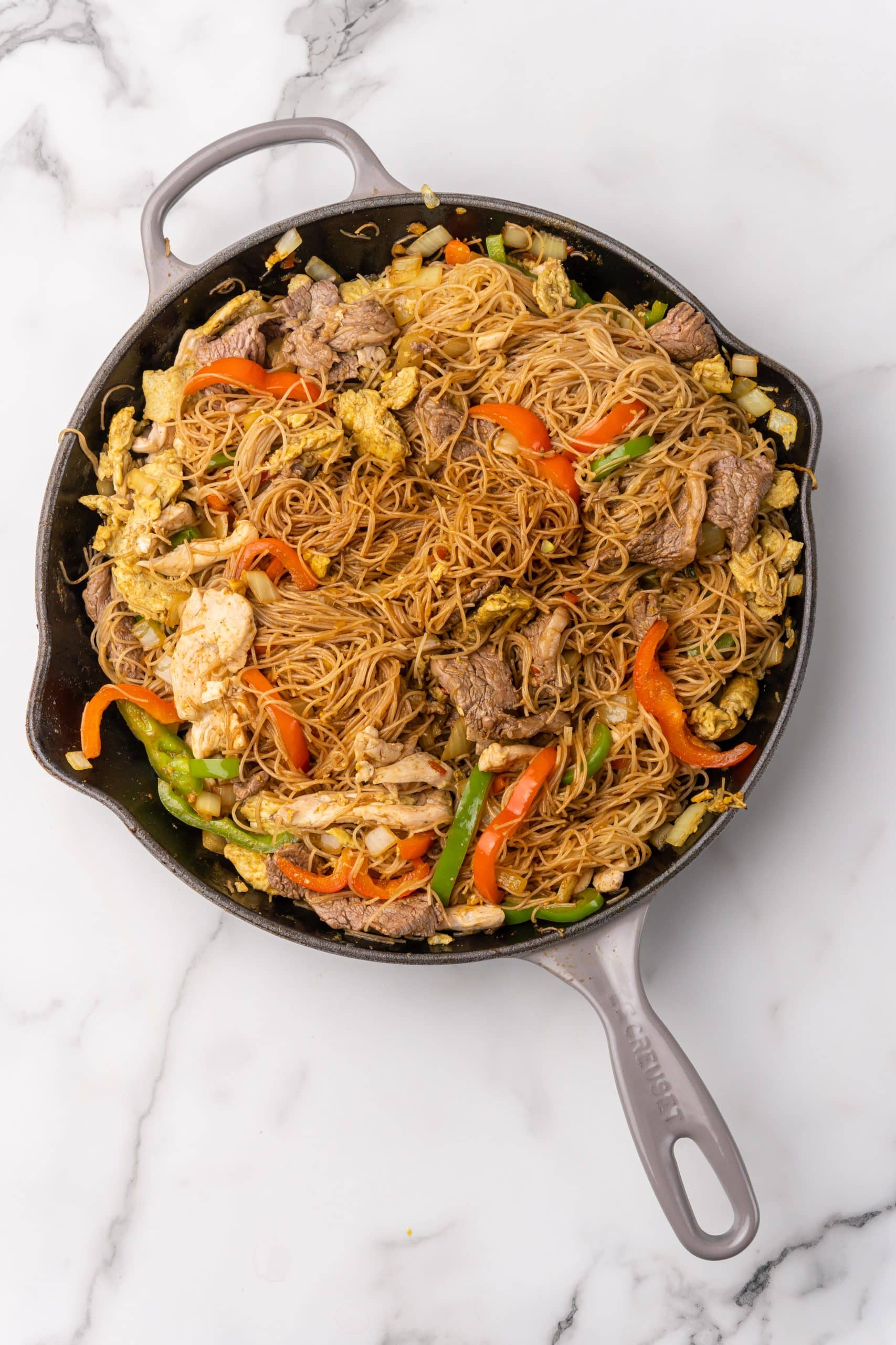 seasoned singapore rice noodle with beef and chicken in a large skillet