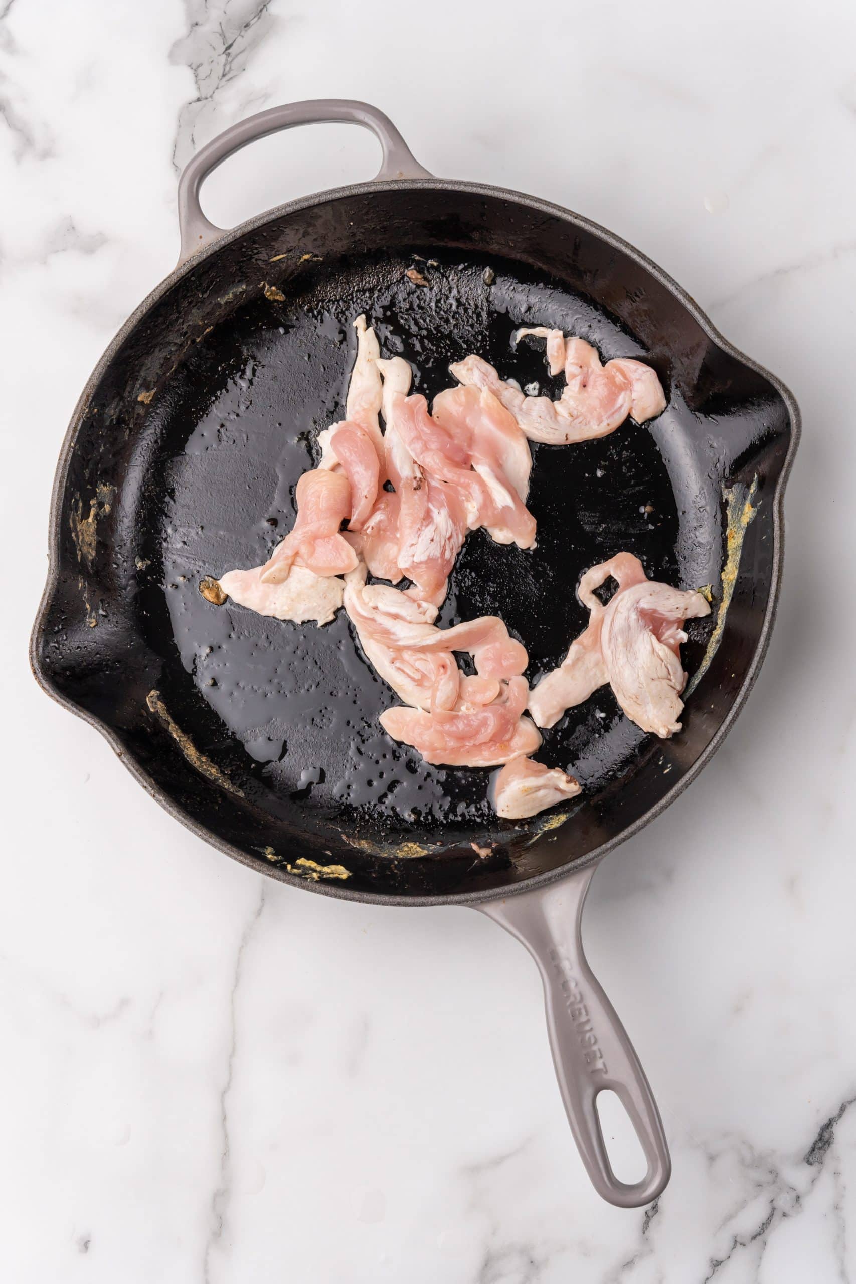 chicken breast strips cooking in a large skillet