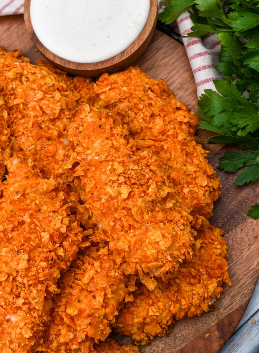 a pile of doritos crusted chicken tenders on a wooden serving tray
