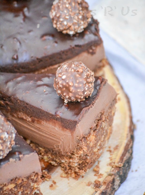 a sliced ferrerro rocher nutella cheesecake on a wooden cutting board