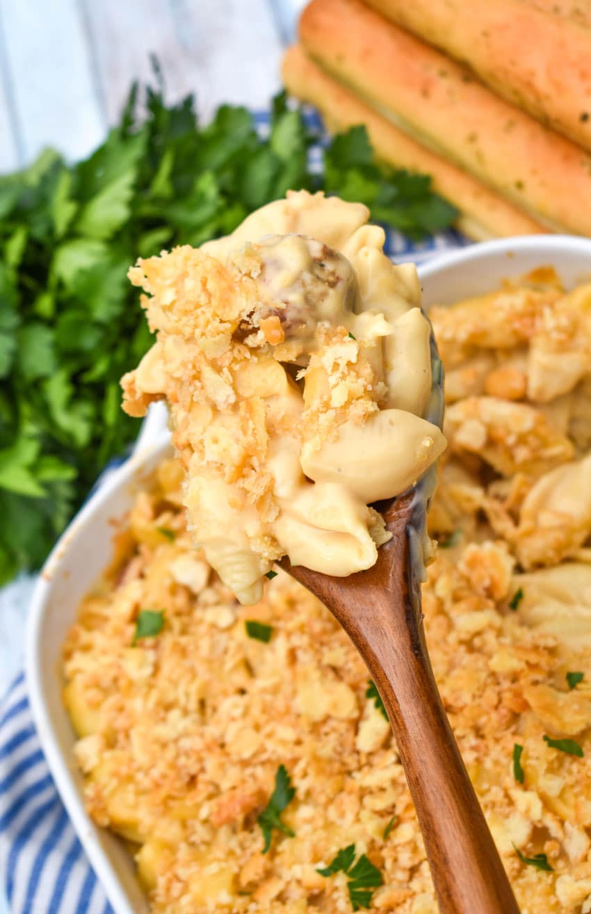 a wooden spoon holding up a scoop of mac and cheese with meatballs