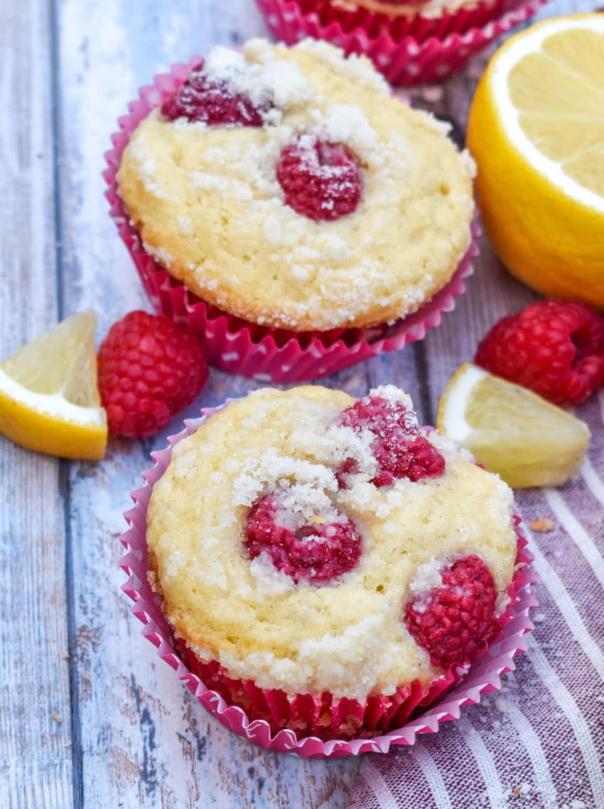 a close up of homemade raspberry lemon yogurt muffins on a wooden table