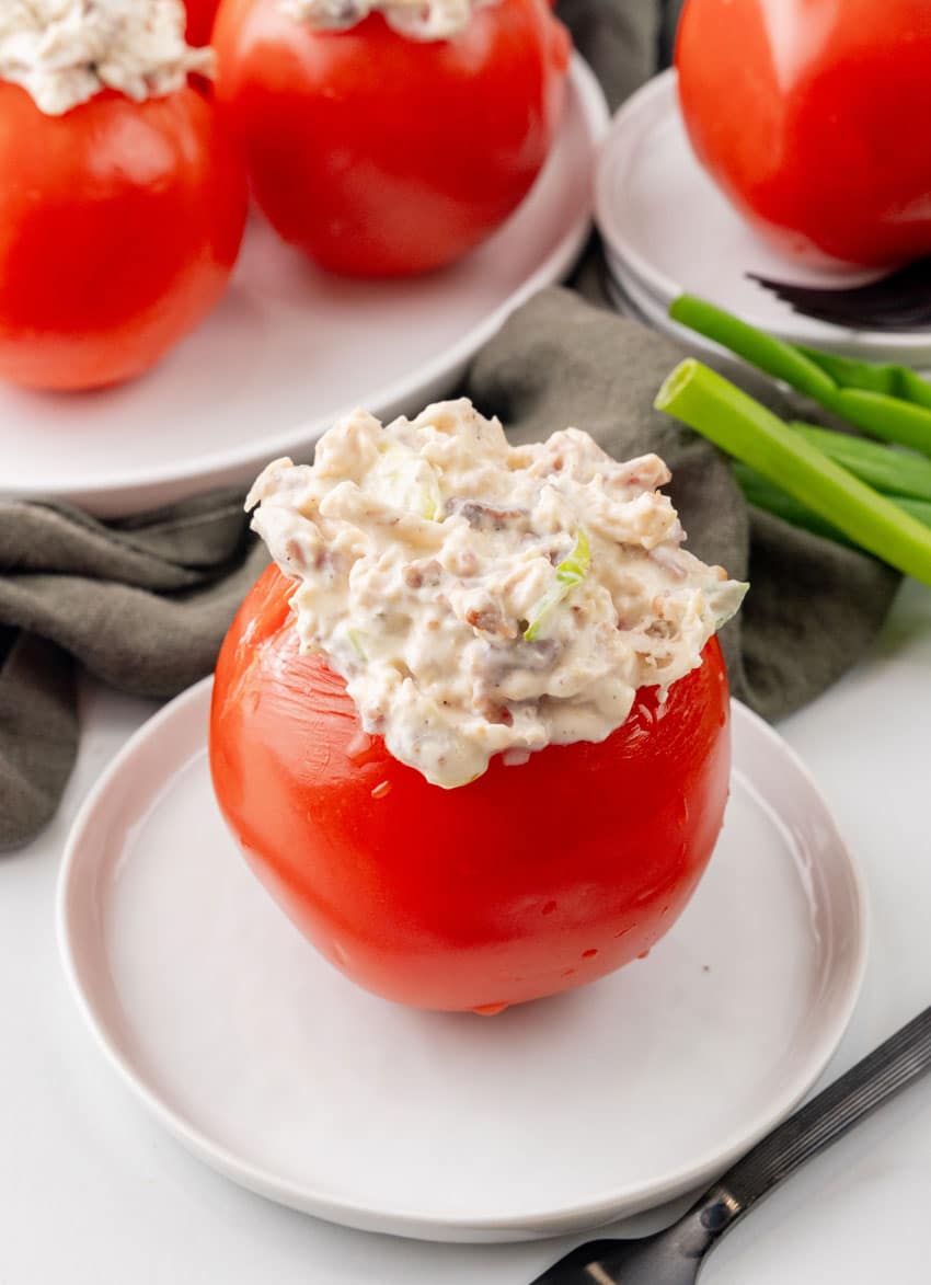 a creamy bacon ranch chicken salad stuffed tomato on a small white plate