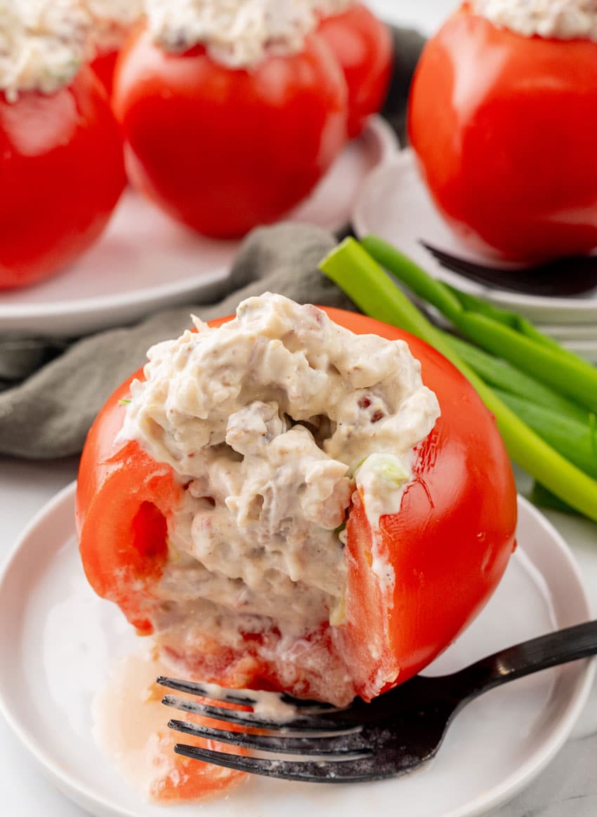a creamy bacon ranch chicken salad stuffed tomato on a small white plate