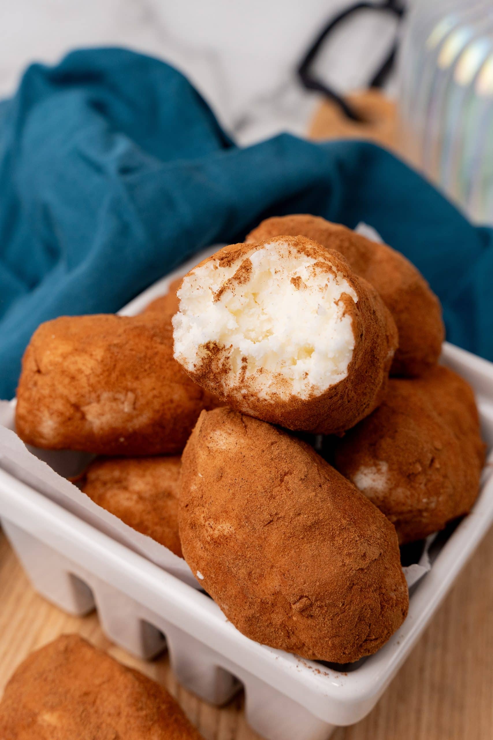 a bitten piece of potato candy resting on top of other whole cinnamon coated coconut candies in a white basket