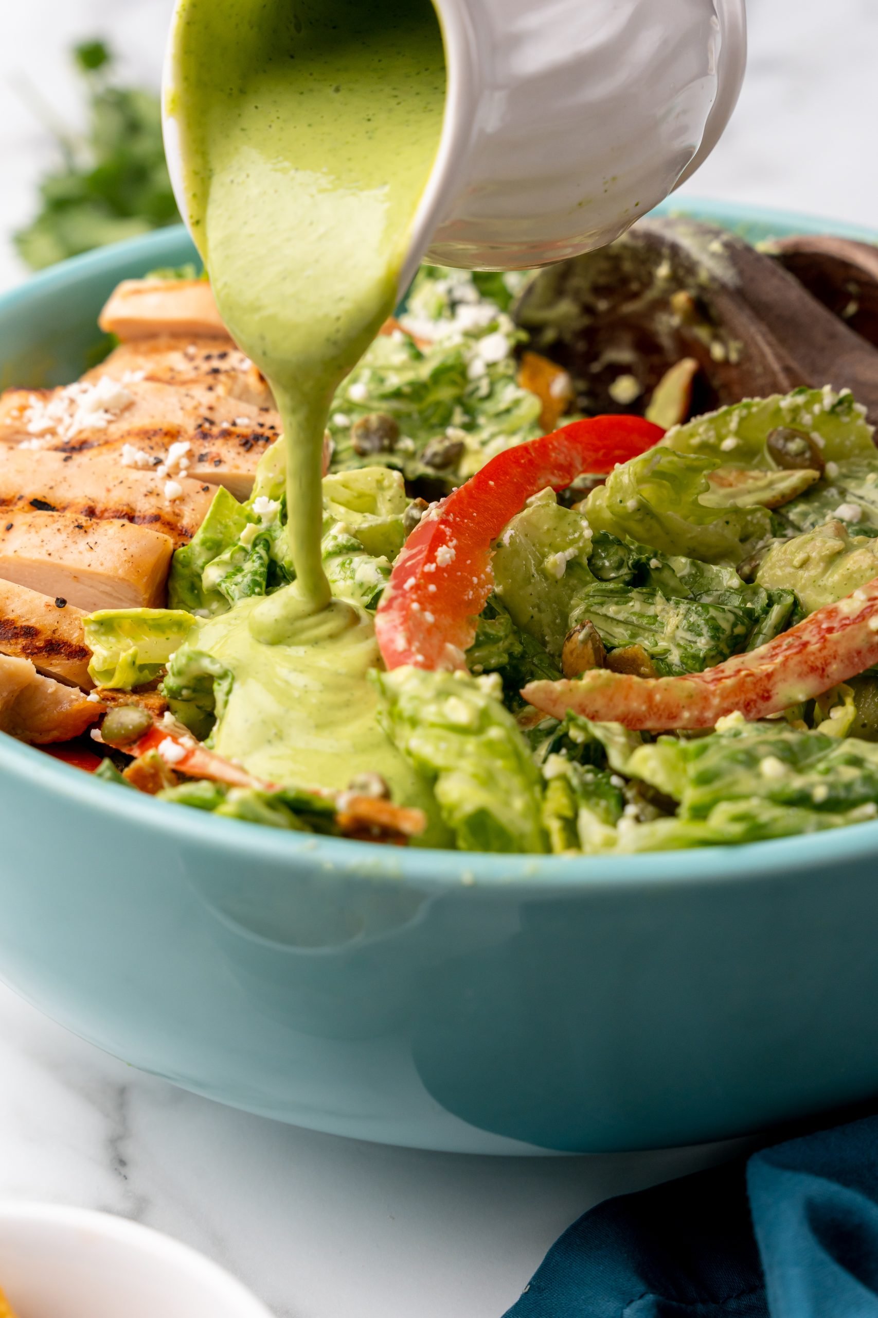 green caesar dressing being poured over Tex Mex salad with chicken
