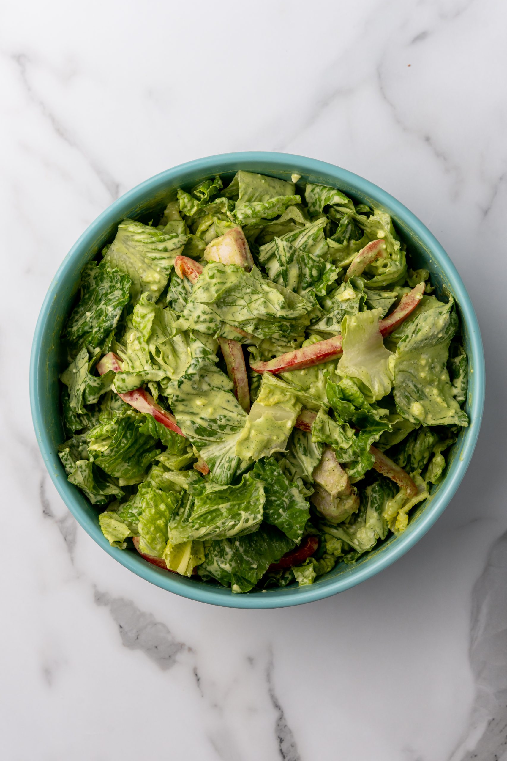 a tossed Caesar salad with Mexican dressing in a blue serving bowl
