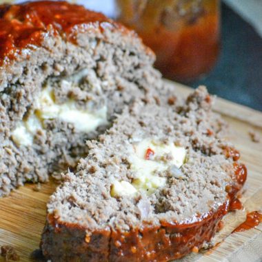 cheese stuffed smoked meatloaf shown sliced on a wooden cutting board