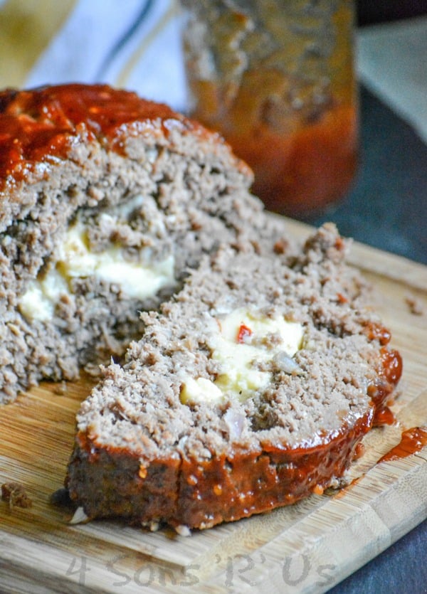 cheese stuffed smoked meatloaf shown sliced on a wooden cutting board