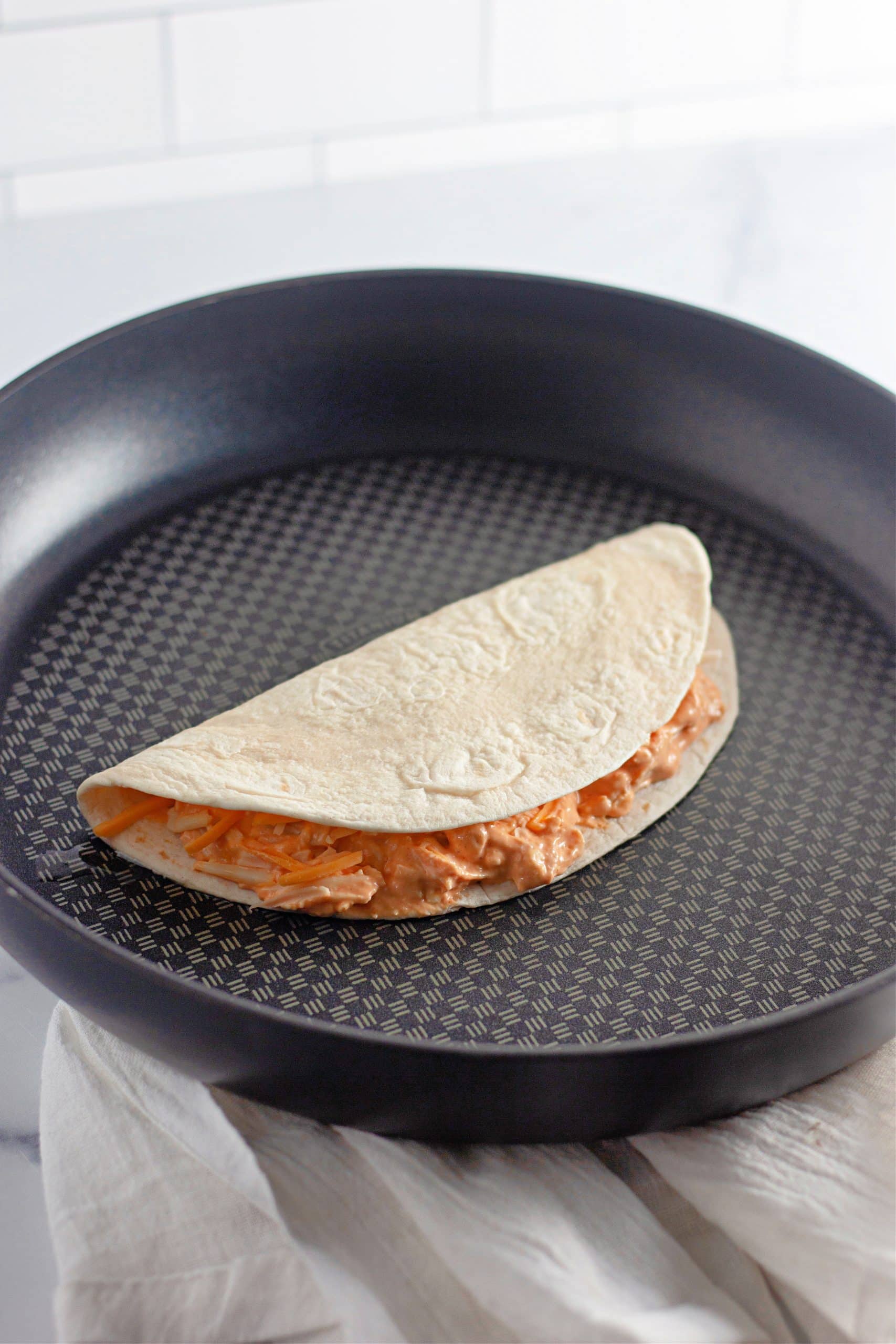 a buffalo chicken quesadilla cooking in a black skillet