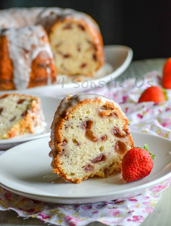 a slice of Glazed Strawberry Lemon Yogurt Cake on a white plate with a fresh strawberry