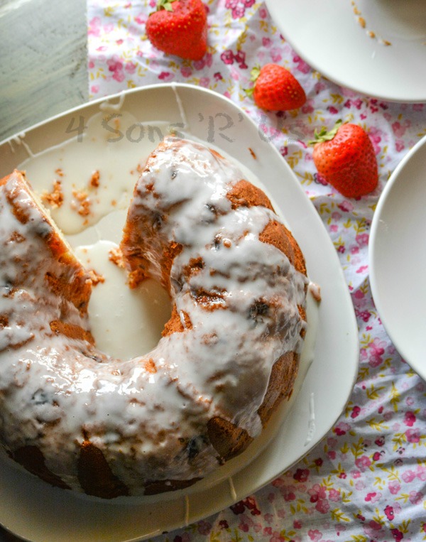 Glazed Strawberry Lemon Yogurt Cake shown with a slice removed and fresh berries off to the side