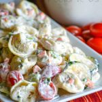 SUMMERTIME TORTELLINI & VEGETABLE PASTA SALAD SERVED ON A WHITE PLATTER