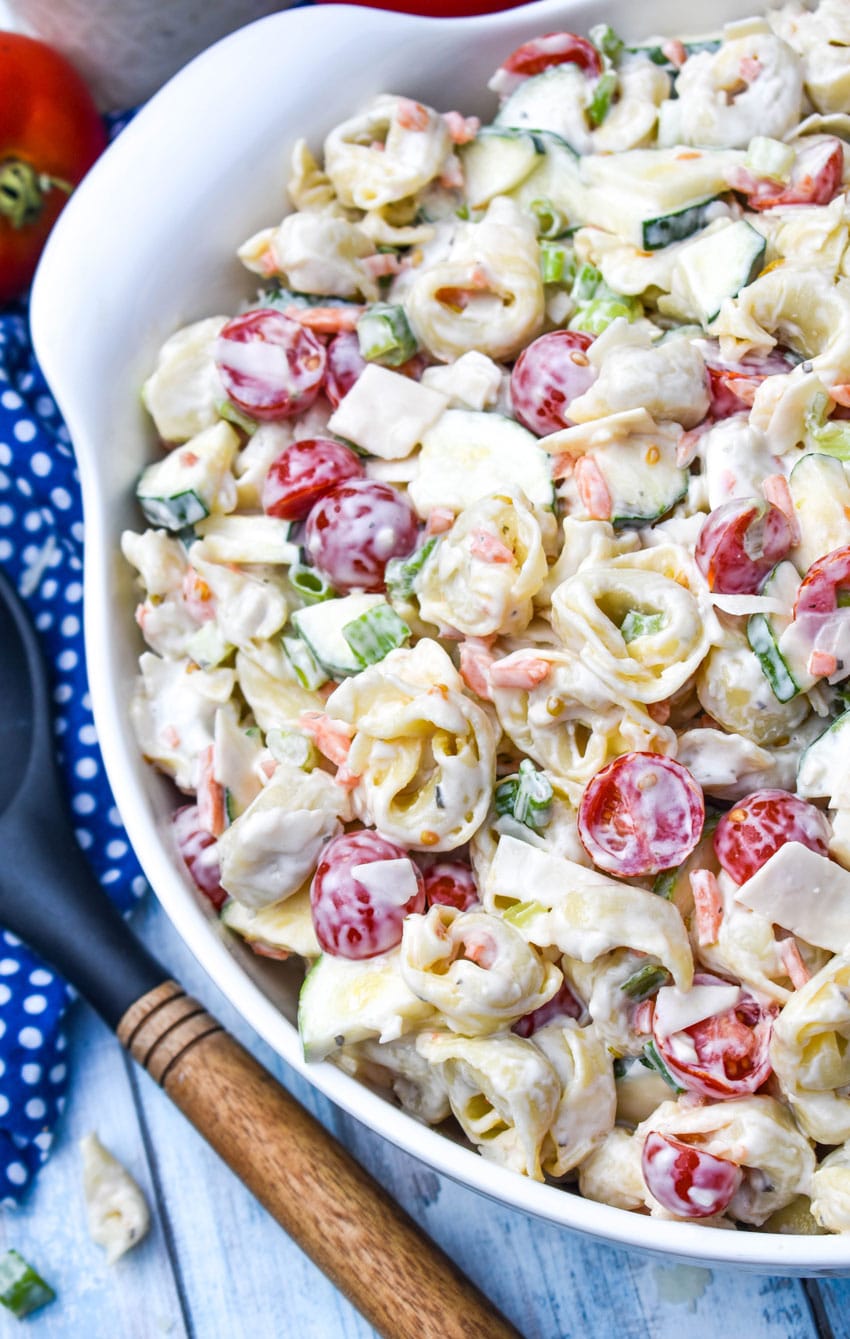 tortellini pasta salad with vegetables in a large white serving bowl