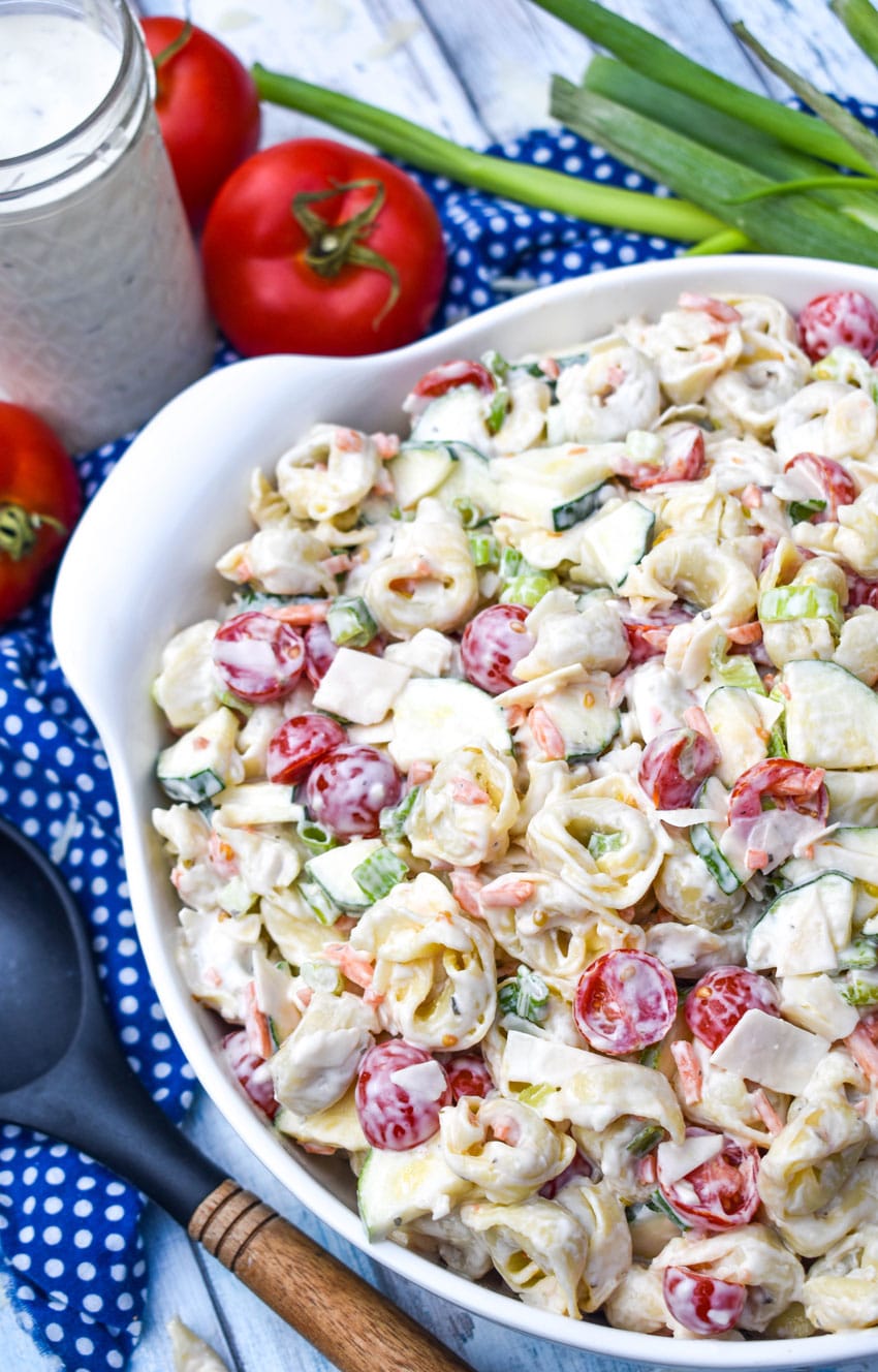 tortellini pasta salad with vegetables in a large white serving bowl
