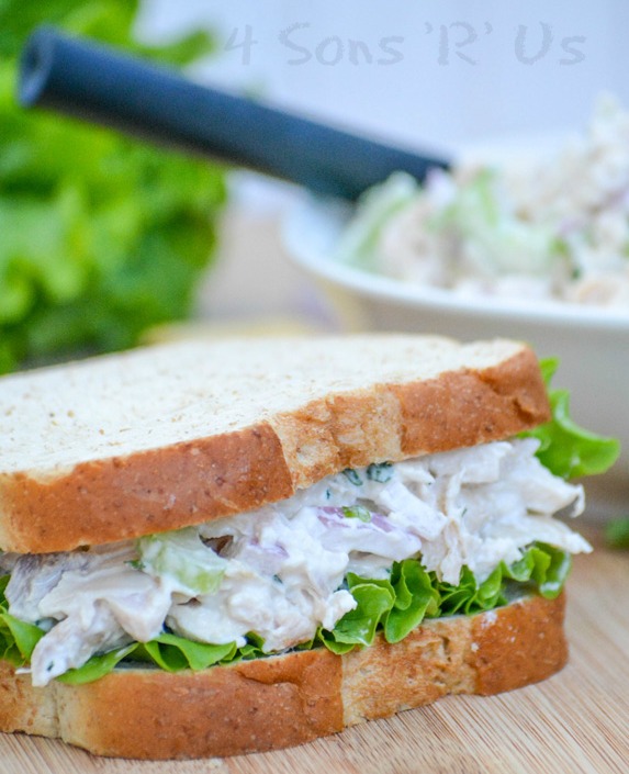 lemon tarragon chopped chicken salad shown between two fluffy pieces of bread with leaf lettuce to make a sandwich