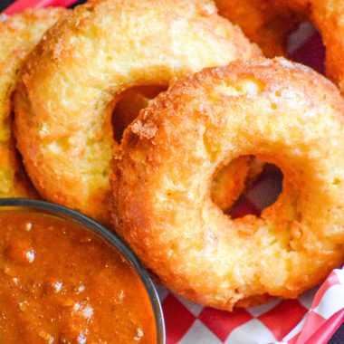 macaroni and cheese donuts in a paper lined plastic food basket with a side of chili for dipping
