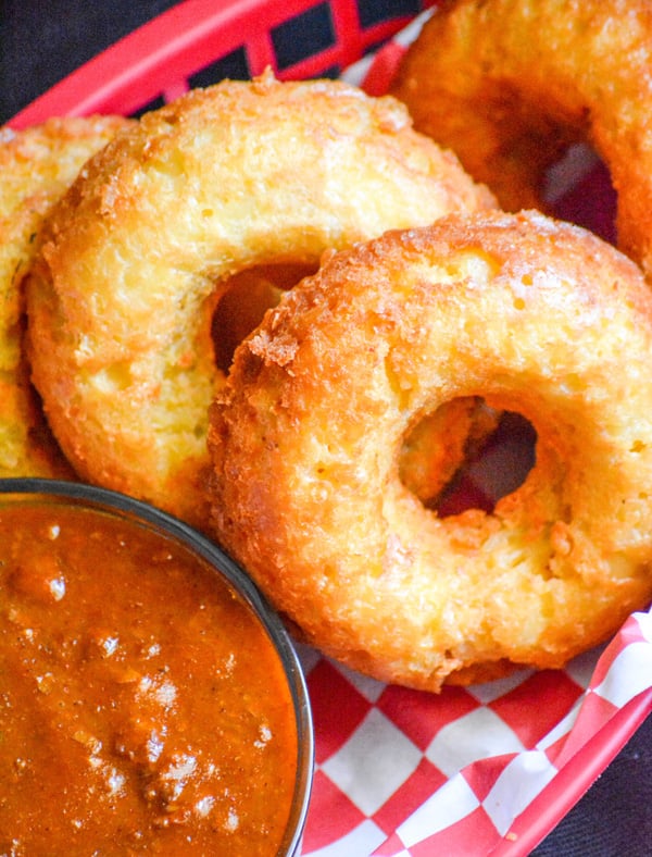 macaroni and cheese donuts in a paper lined plastic food basket with a side of chili for dipping