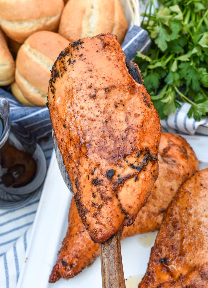a wooden spatula holding up a maple chipotle smoked chicken breast