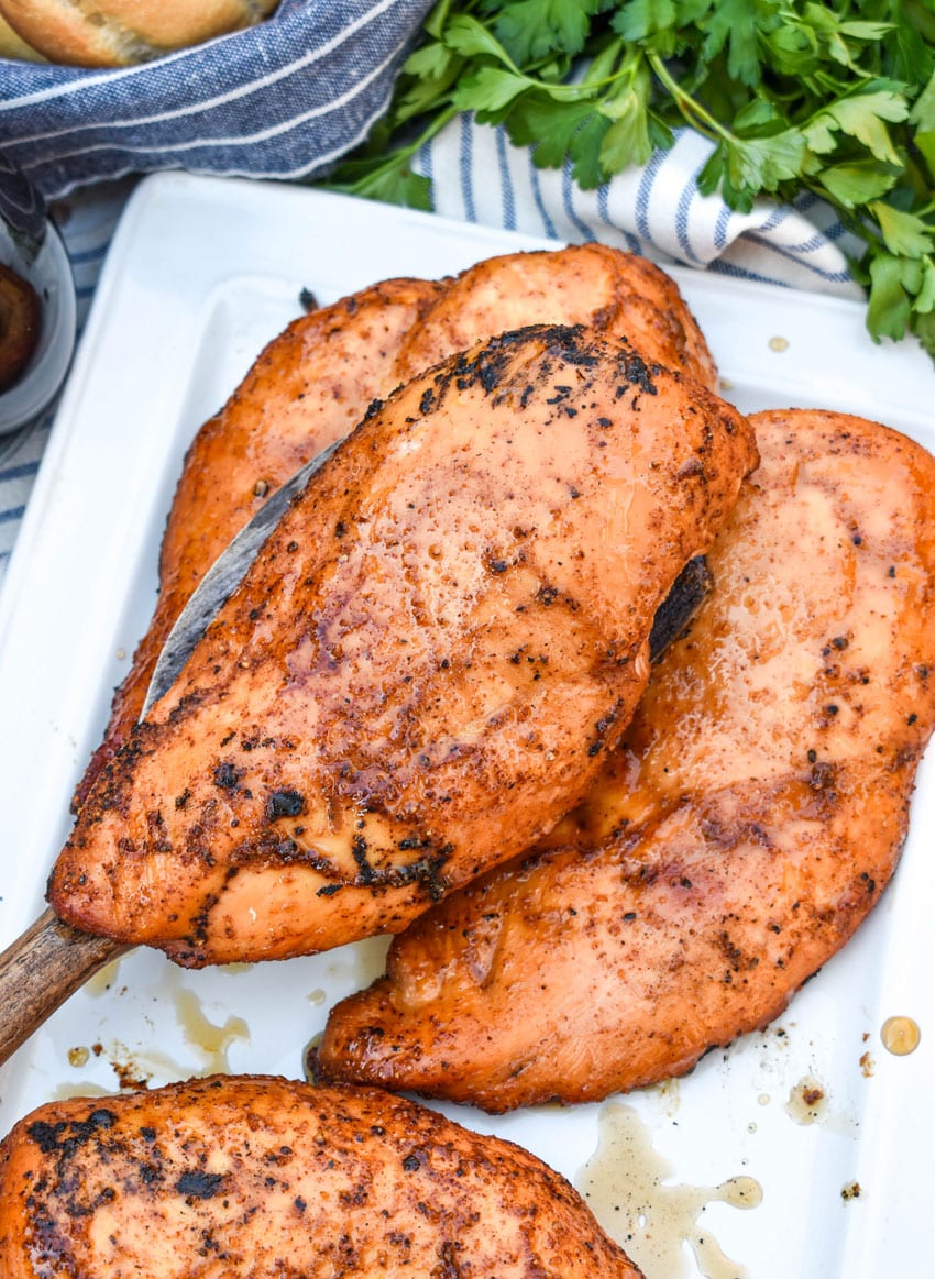 a wooden spatula holding up a maple chipotle smoked chicken breast