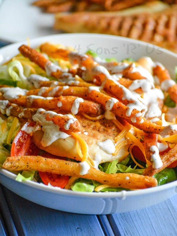 french fry topped pittsburgh salad with chicken in a white bowl