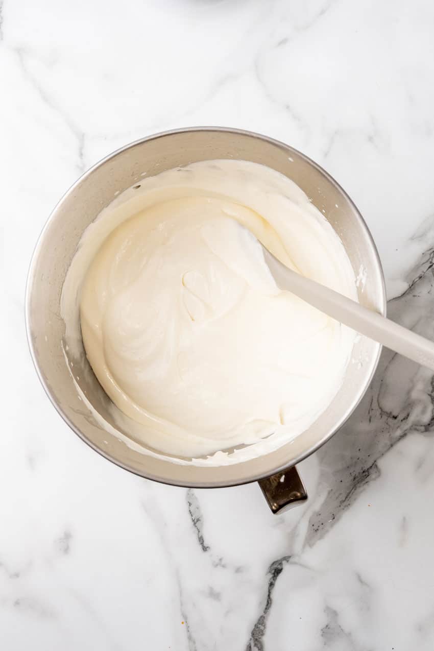 sweetened condensed milk mixed with whipped cream in a metal mixing bowl