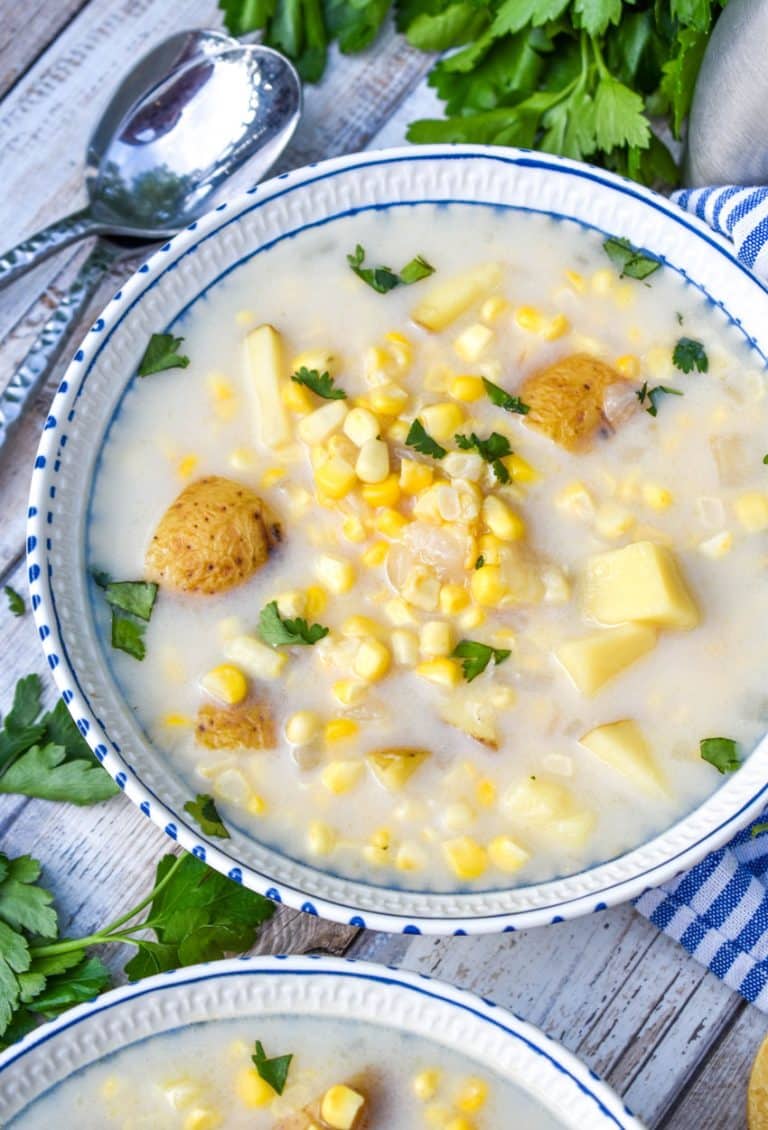 corn off the cobb soup in white bowl topped with fresh chopped green herbs