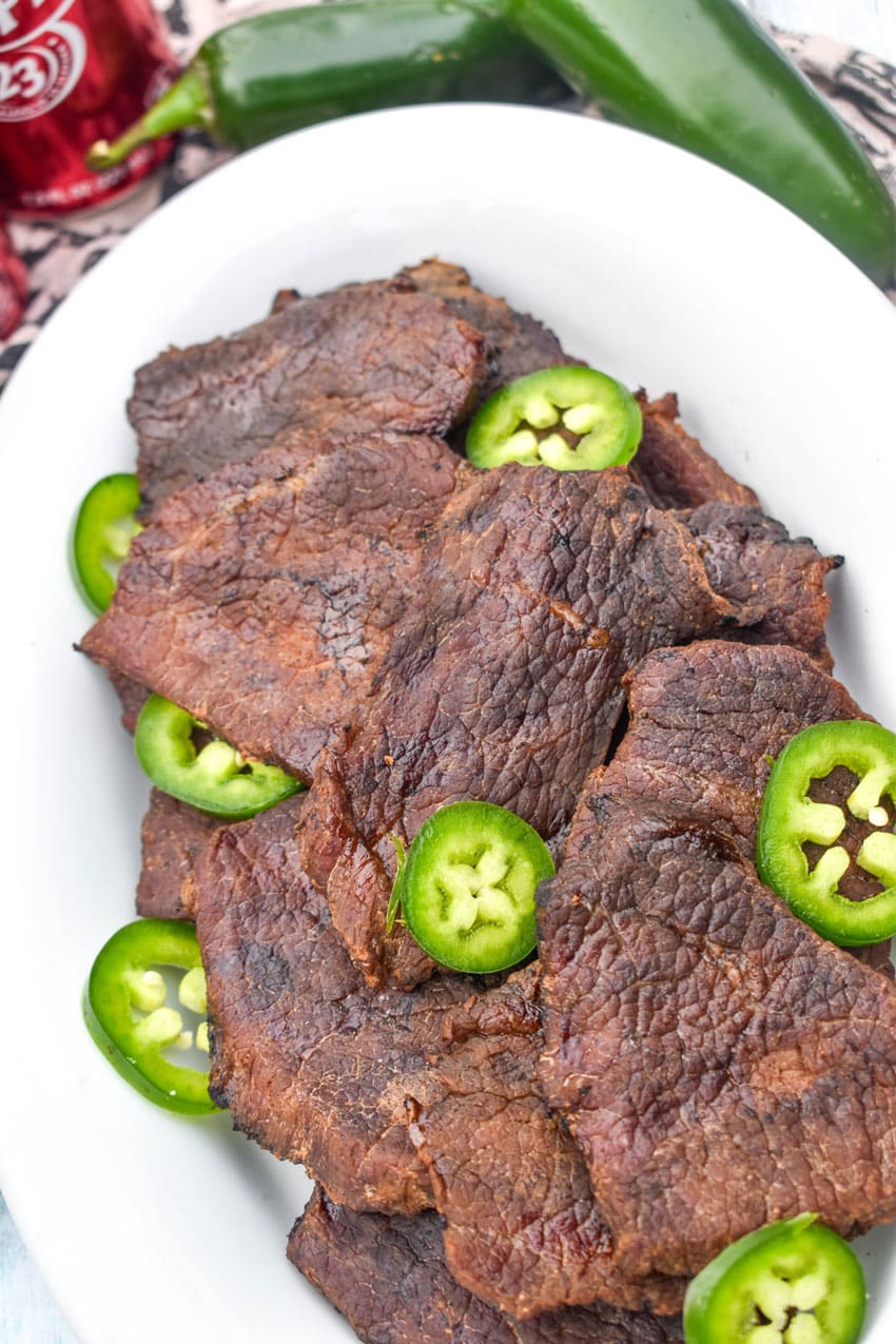 dr pepper jalapeno smoked beef jerky pieces with jalapeno slices in a white serving platter