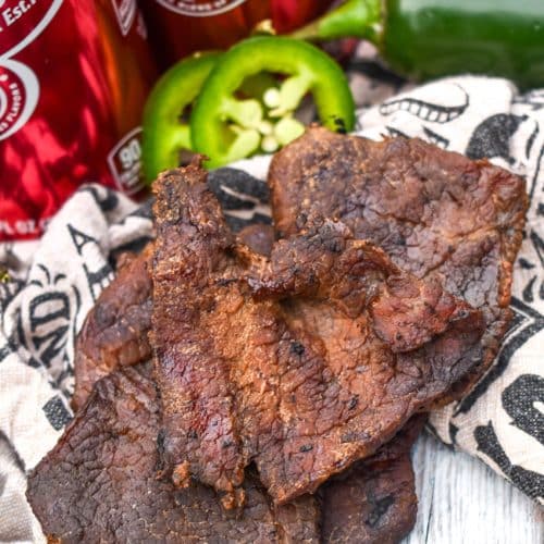 strips of homemade spicy smoked beef jerky on a wooden table