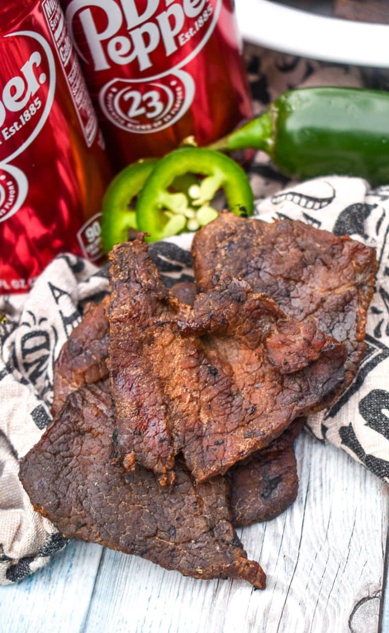 strips of homemade spicy smoked beef jerky on a wooden table