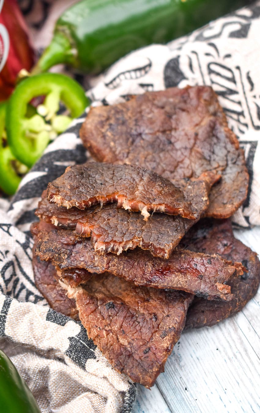 strips of homemade spicy smoked beef jerky on a wooden table