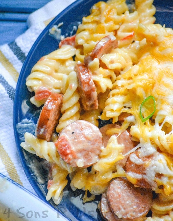 Spicy Sausage and Pasta Casserole shown on a navy blue plate set on top of a striped dish cloth