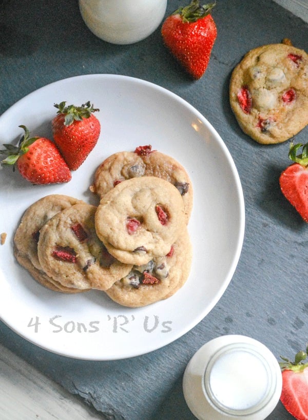 THREE STRAWBERRY CHOCOLATE CHIP COOKIES ON A WHITE PLATE WITH FRESH STRAWBERRIES ON THE SIDE