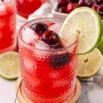 sweet black cherry limeade with ice in a small glass on a wooden coaster