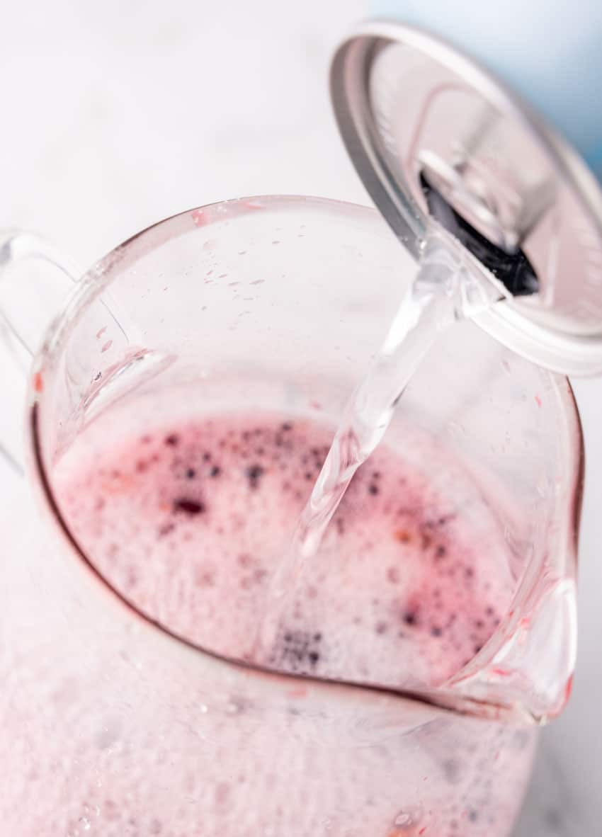 sparkling water being poured into a glass pitcher