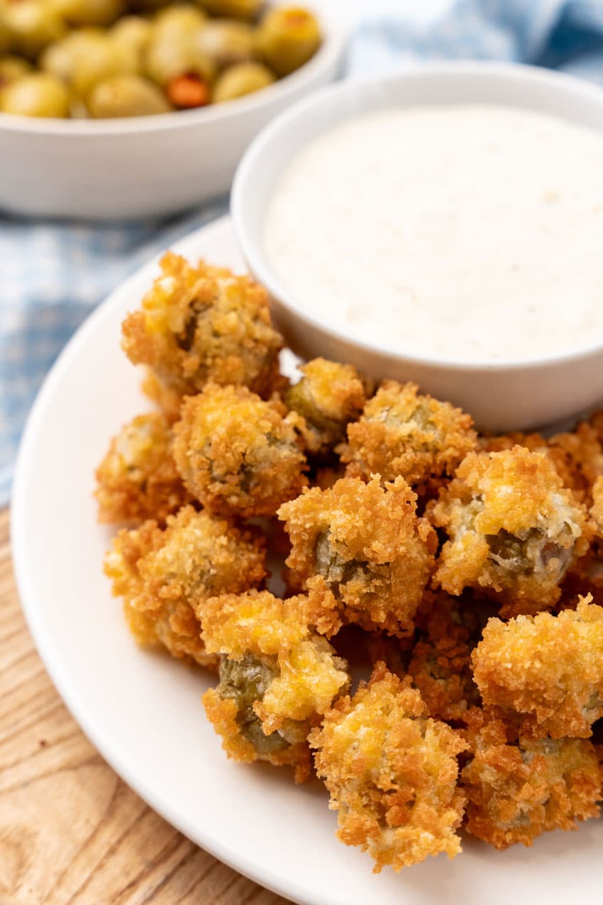 fried olives with a bowl of garlic aioli on a white plate