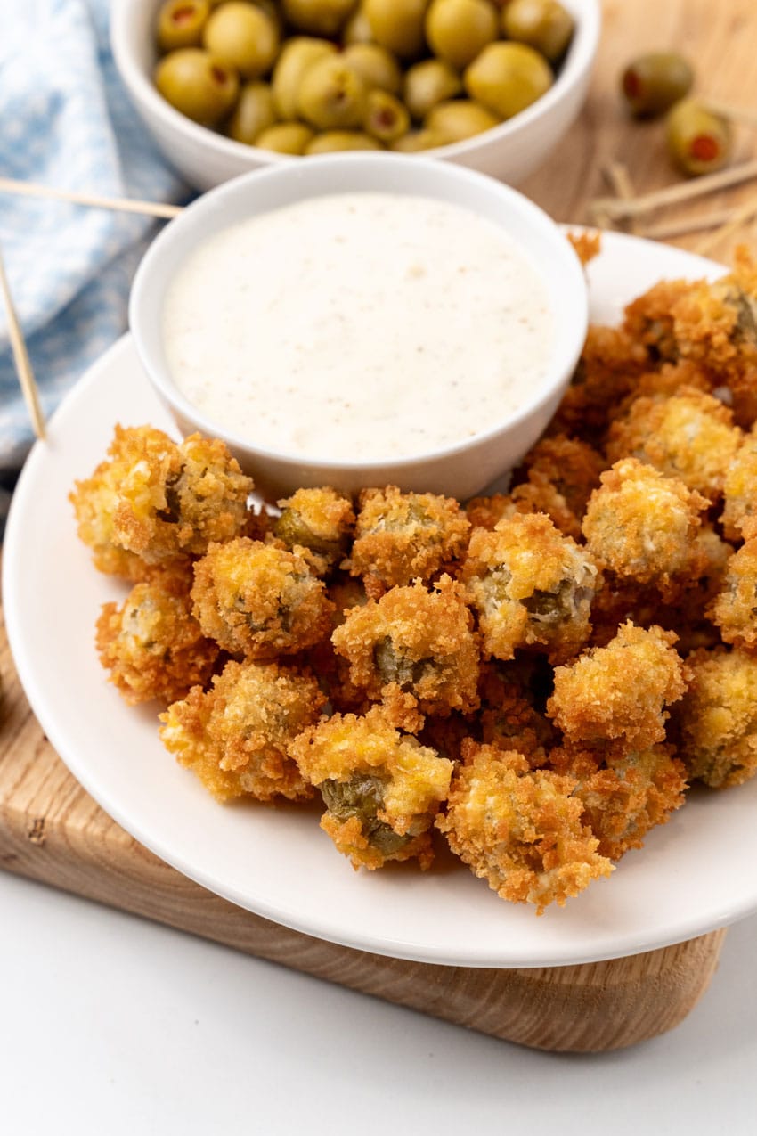 fried olives with a bowl of garlic aioli on a white plate