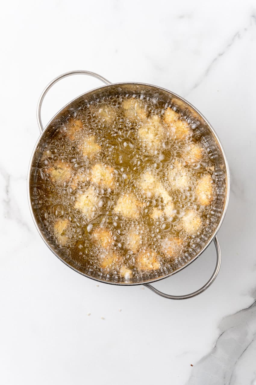 panko bread crumb coated olives frying in hot oil in a metal pot