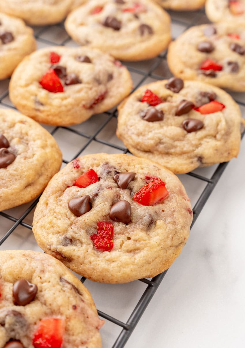 a close up of strawberry chocolate chip cookies on a wire rack