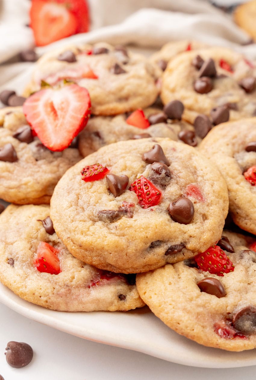a pile of strawberry chocolate chip cookies on a white serving plate