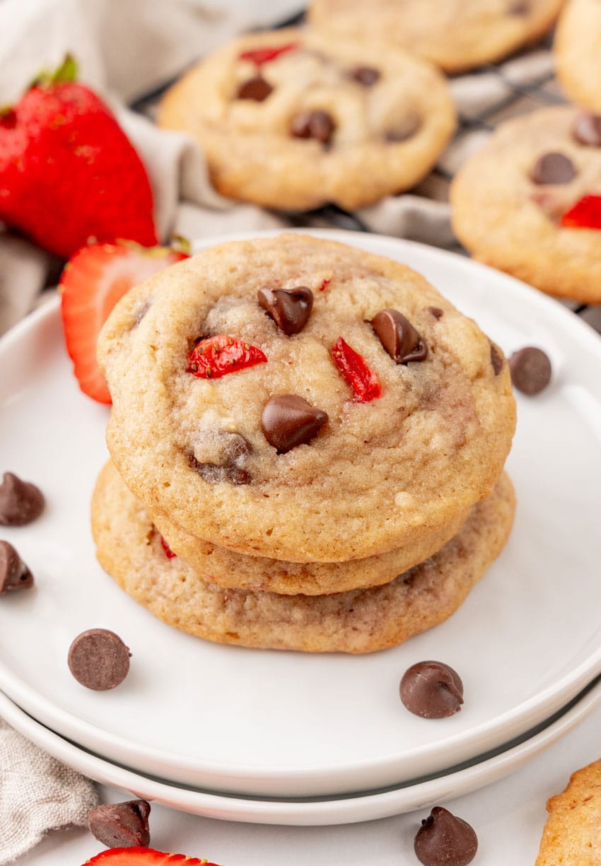 a stack of three strawberry chocolate chip cookies on a small white plate