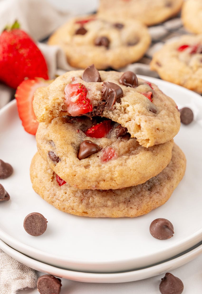 a stack of three strawberry chocolate chip cookies on a small white plate
