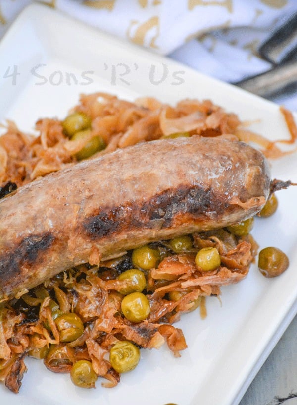 seared beer bratwurst over a bed of caramelized sauerkraut on a white plate