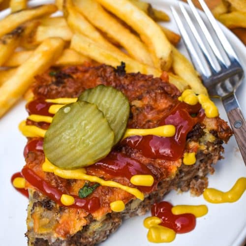 a slice of cheeseburger pie topped with ketchup and mustard next to crispy french fries on a white plate